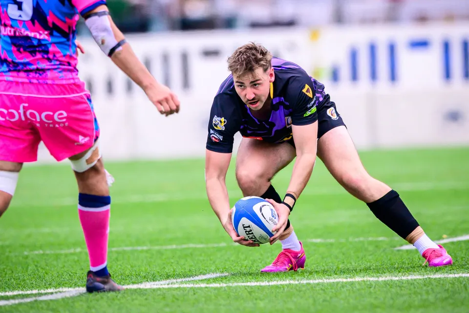 Tens Selects player crouches low to pick up the ball while an OSOB player in pink stands close beside him