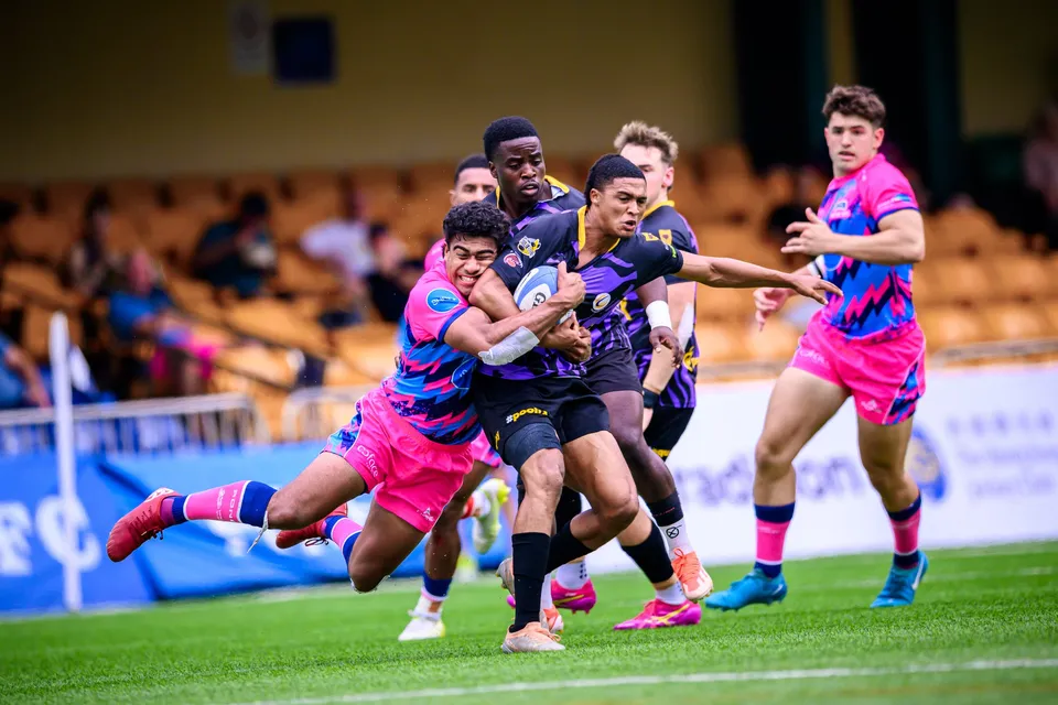 OSOB players bring down a Tens Selects ball carrier near the touchline as teammates in purple and pink run in
