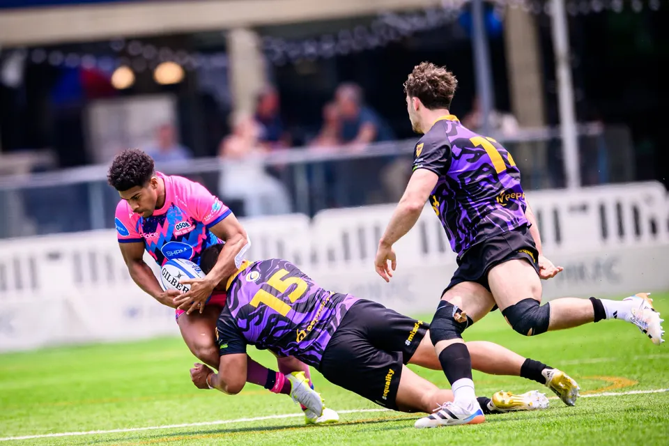 OSOB ball carrier is tackled low by a Tens Selects number 15 as a purple number 14 steps in beside him