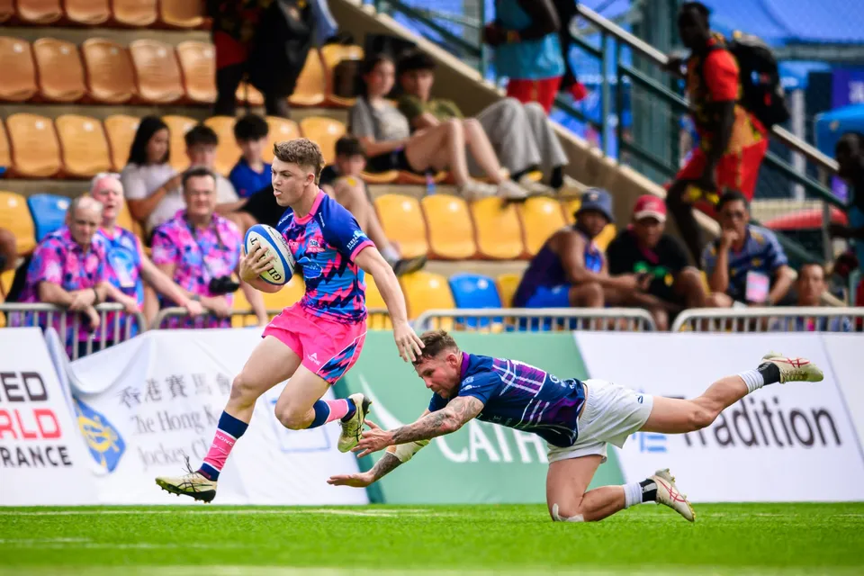 OSOB winger in pink races along the touchline with the ball as a Scottish Exiles player slides at his feet