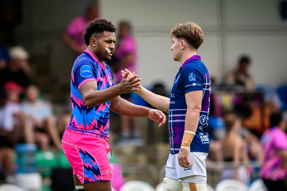 An OSOB player in pink and a Scottish Exiles player in navy and purple shake hands during the match