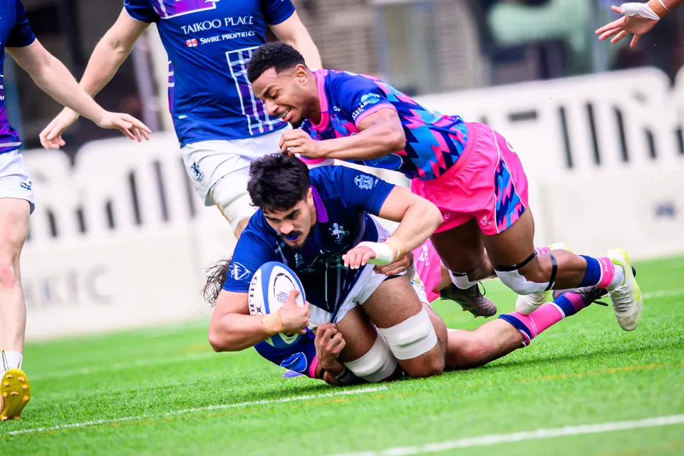 Exiles ball carrier is dragged to the ground by an OSOB player in pink as another Exiles player closes in