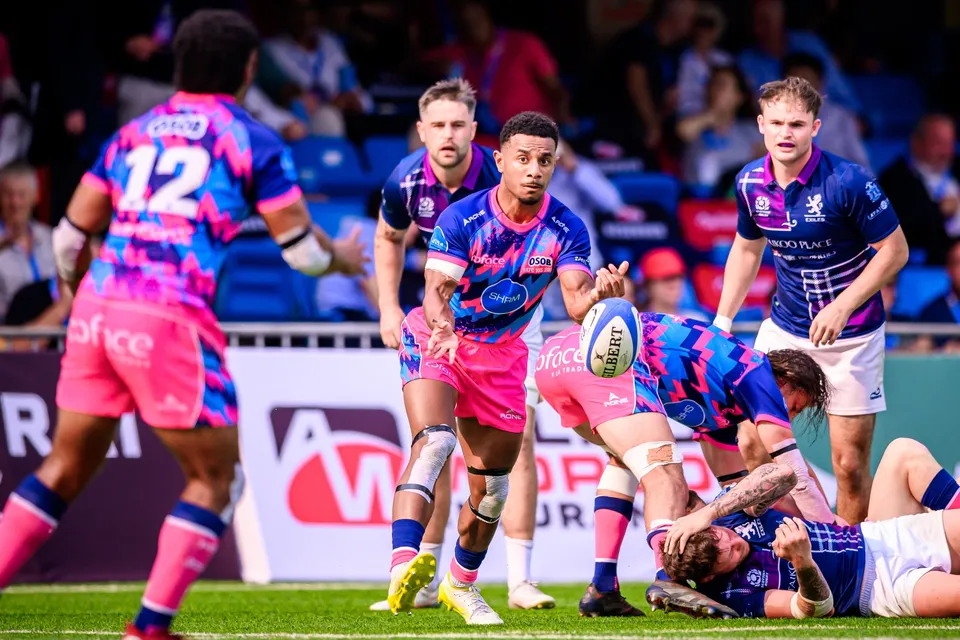 OSOB scrum-half in pink fires out a pass as number 12 runs ahead and an Exiles player waits behind