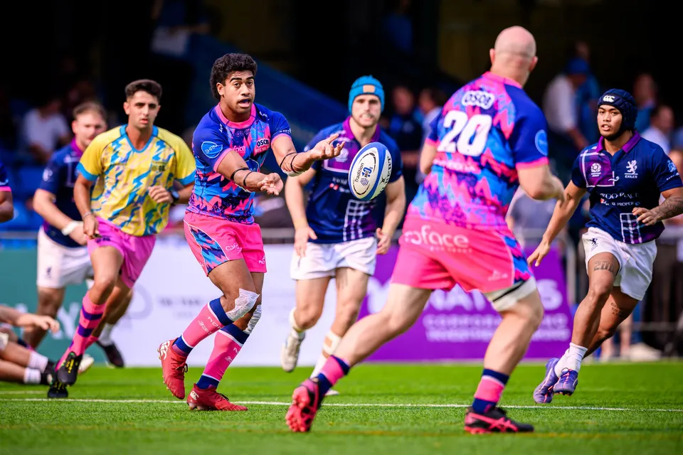 OSOB player passes wide from a ruck while number 20 and a player in yellow and blue move up in support
