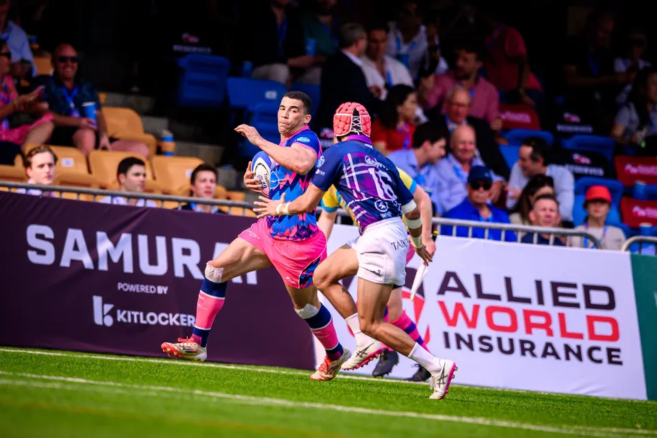 OSOB ball carrier runs the touchline past Samurai and Allied World banners with an Exiles player in a red cap chasing
