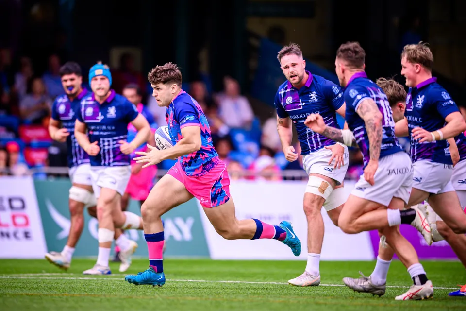 OSOB ball carrier surges forward with the ball as four Scottish Exiles players in navy and purple chase him down