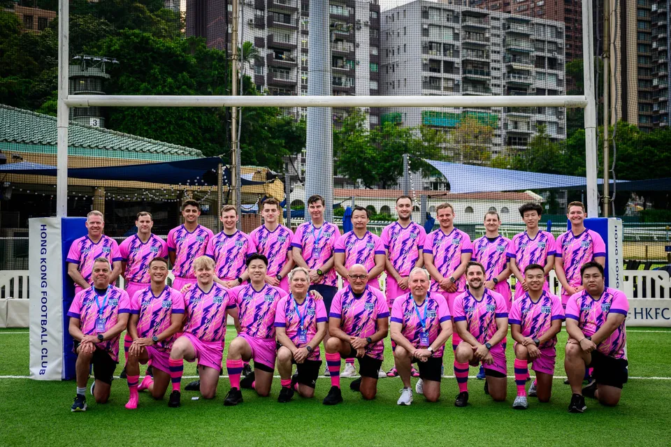 OSOB squad in pink and blue shirts pose in two rows in front of the posts, Hong Kong Football Club, 2026