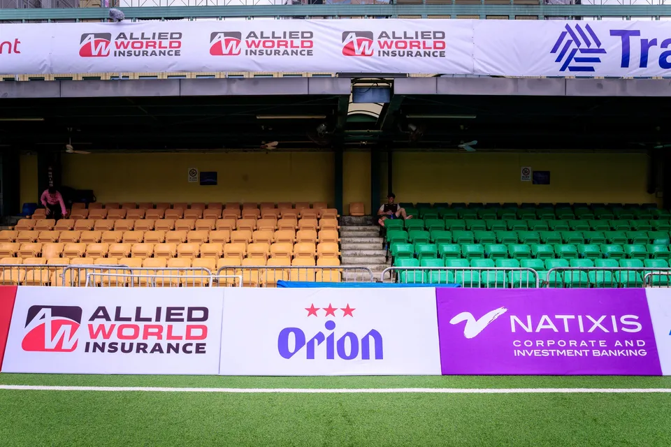Stand with orange and green seats, Allied World Insurance and Tradition banners above, one person on the steps