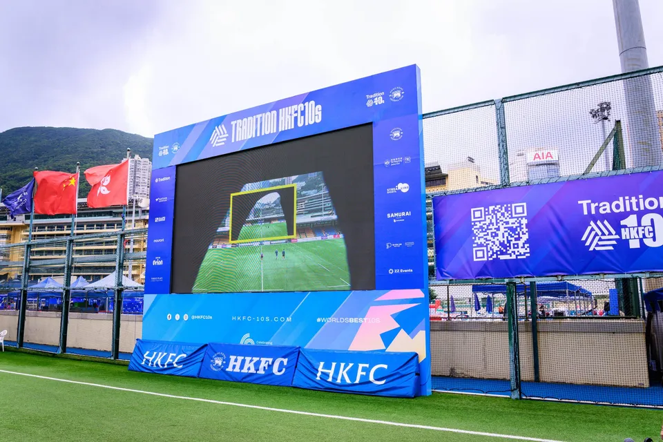 Ground level view of white HKFC boards with the club crest on artificial turf, netting behind