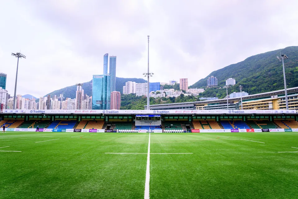 Wide view of the HKFC pitch from the halfway line with the main stand and tall towers behind