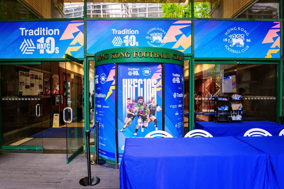 Blue Tradition HKFC 10s archway at the club corridor entrance, with a member offer sign and a player poster
