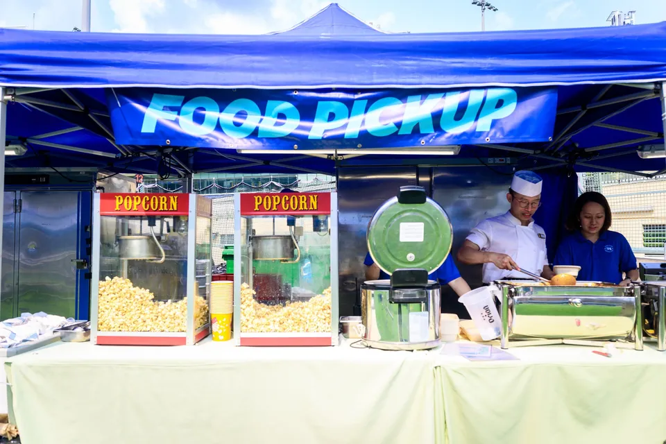 Food Pickup stall with two popcorn machines and two staff in white and blue behind the counter